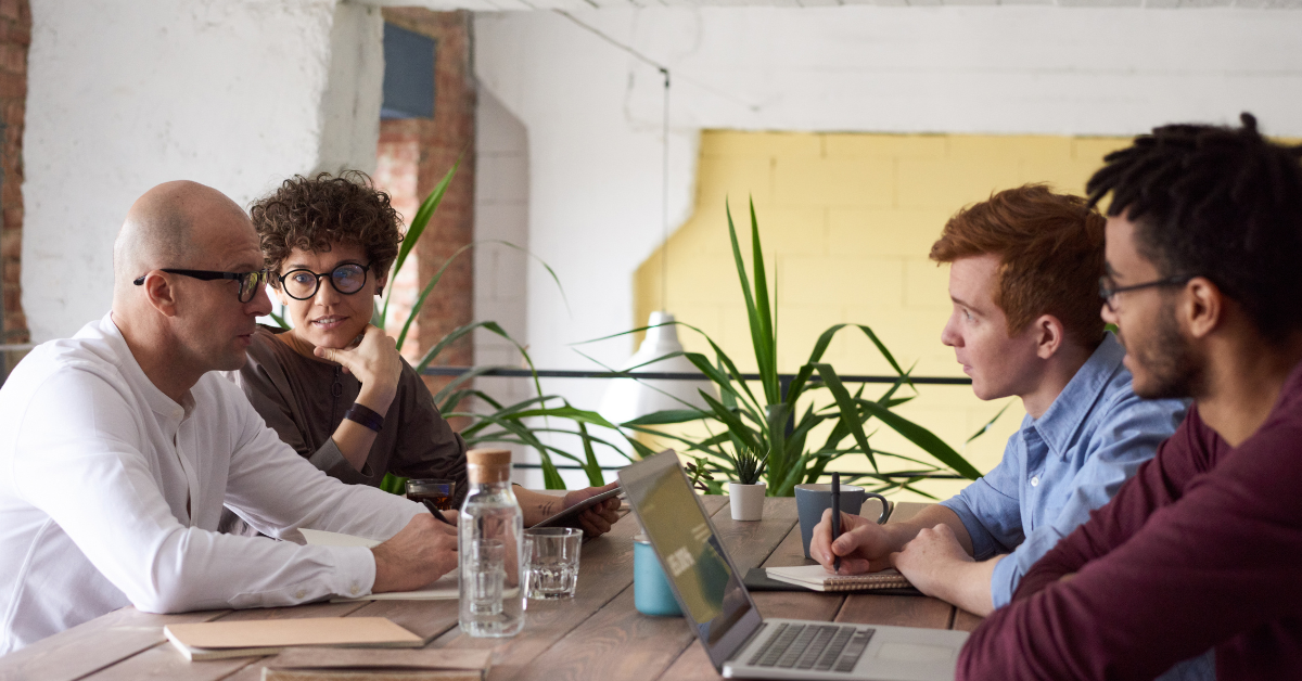 colleagues discussing around a table and laptops